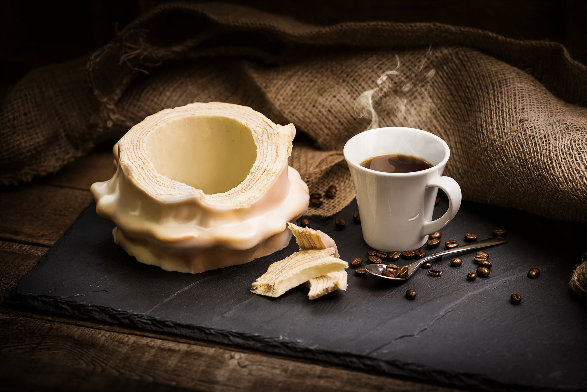 Weißer Baumkuchen aufgeschnitten schön drapiert mit einer kleinen Kaffeetasse.